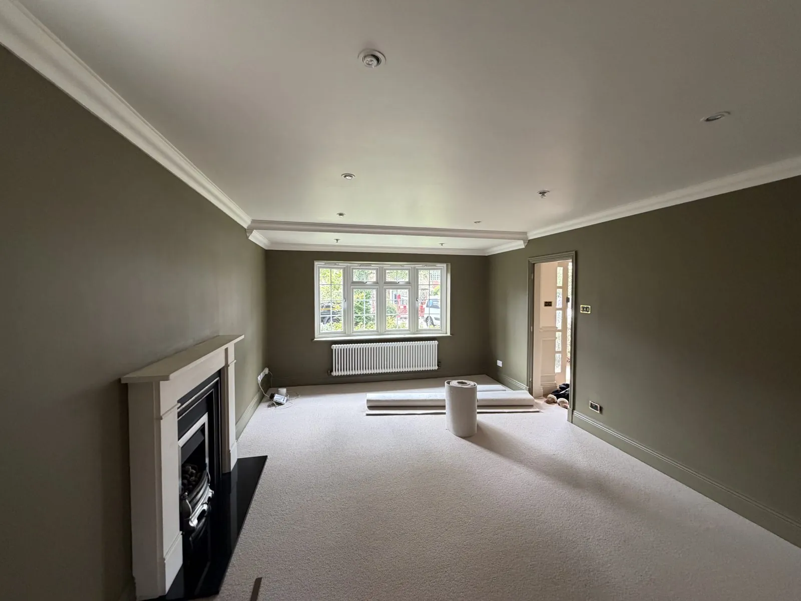 Freshly painted sage green living room with crisp white coving by J&F Decor